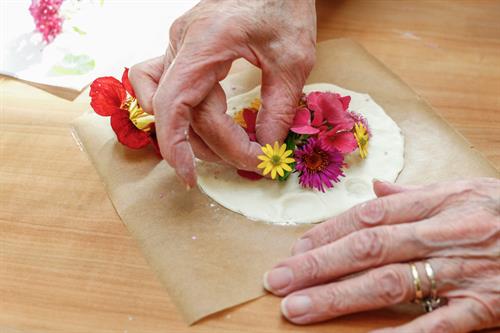 Hände, die Blumen auf einem Tisch halten
